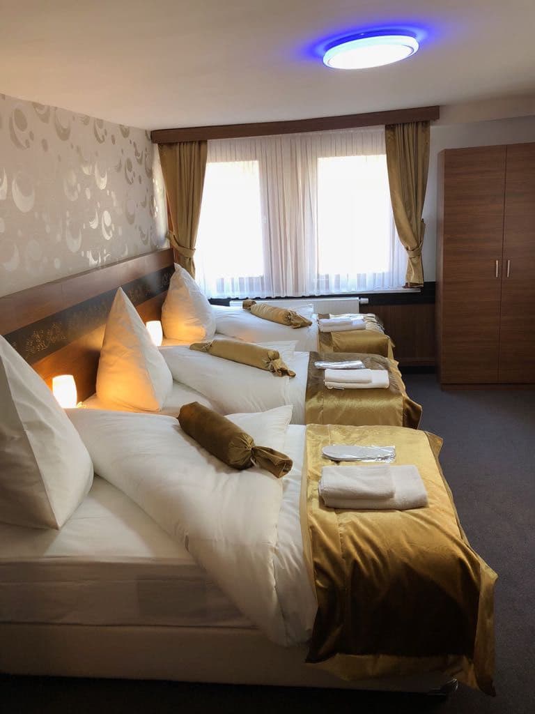 Helles Hotelzimmer mit Doppelbett, Fenster und Teppichboden.