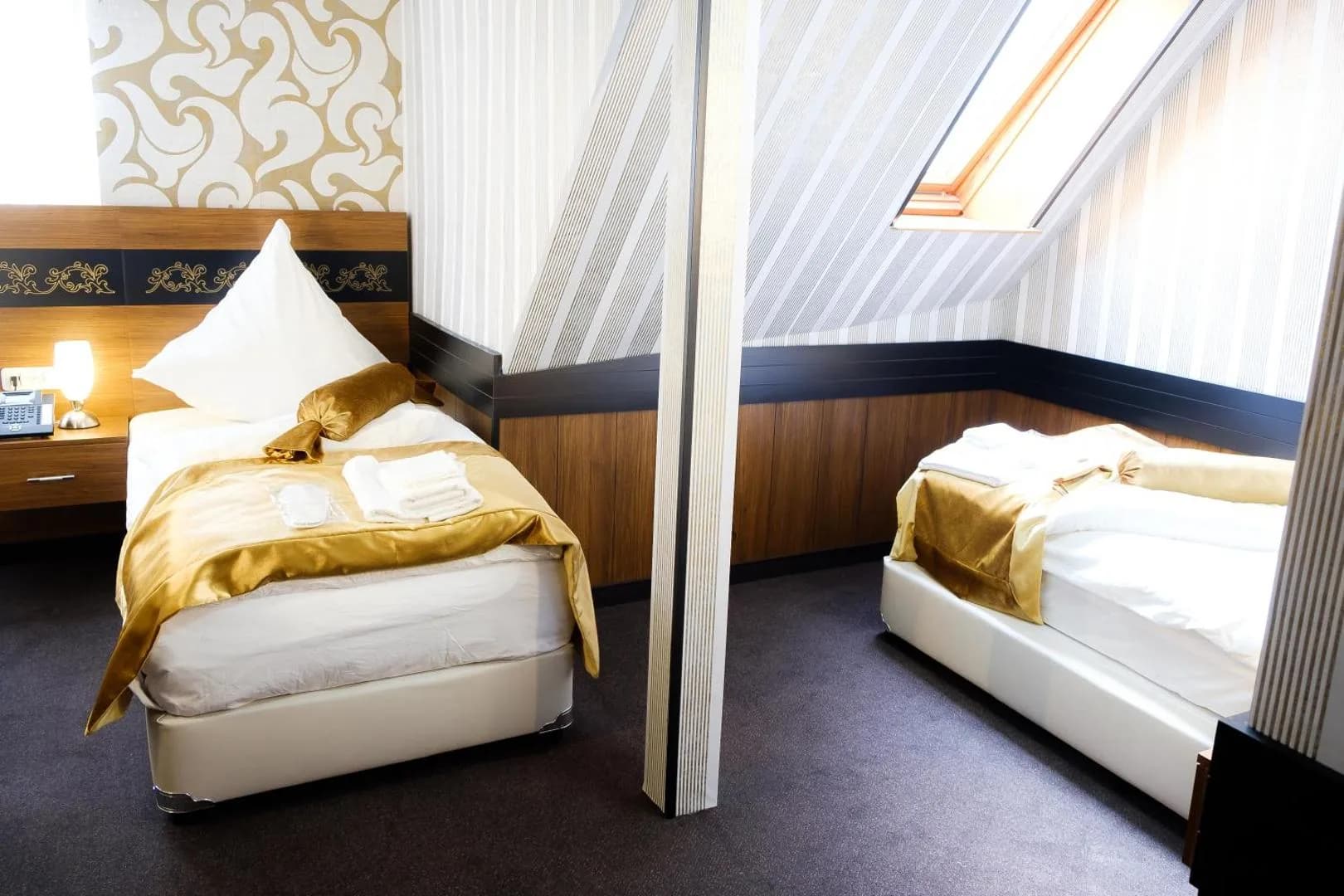 Helles Zweibettzimmer mit zwei Einzelbetten unter dem Dachfenster