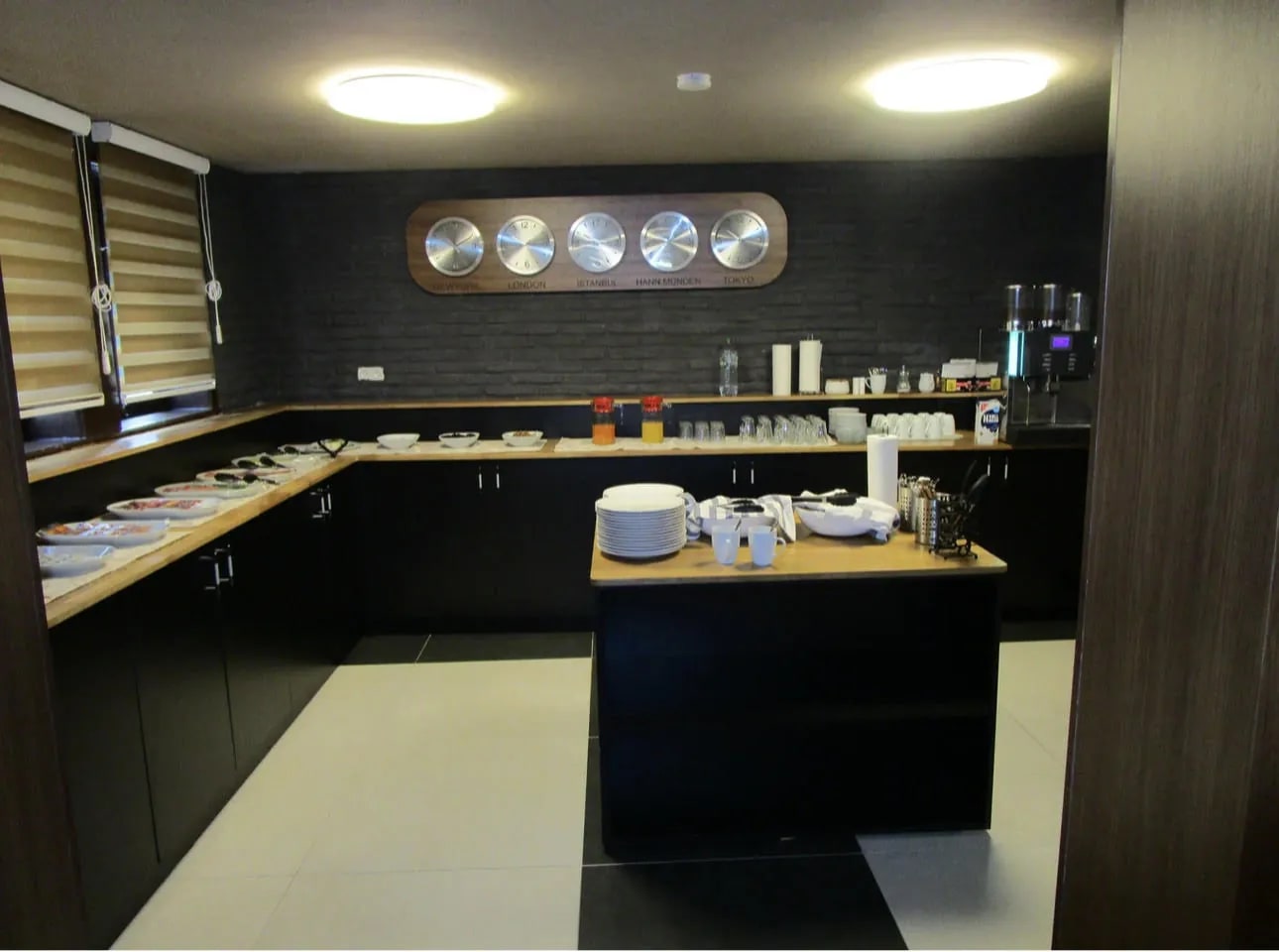 Frühstücksbuffet mit Weltzeituhren, Kaffeemaschine und bereitstehendem Geschirr