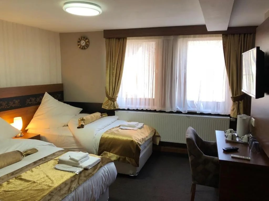 Dreibettzimmer bei Tageslicht mit Fensterfront und Schreibtisch