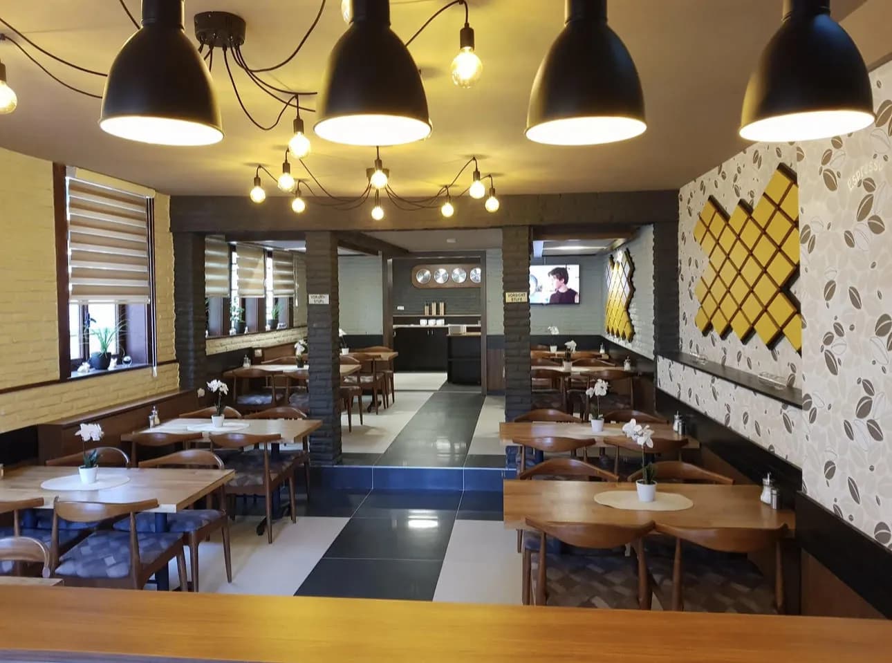 Frühstücksraum mit eingedeckten Tischen, Stühlen und Blick zum Buffetbereich