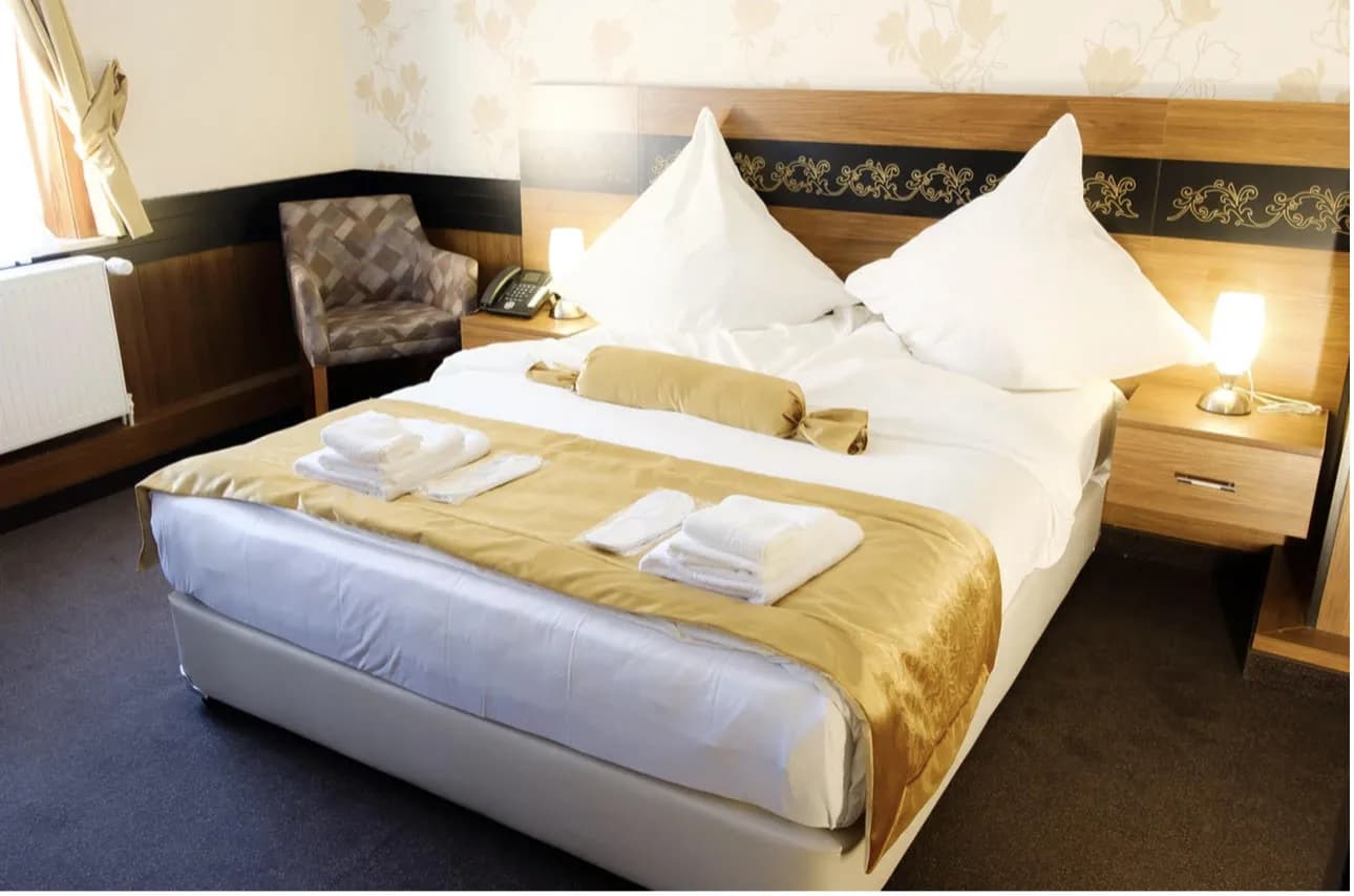 Doppelzimmer mit dezenter Blumentapete und gemütlichem Sessel