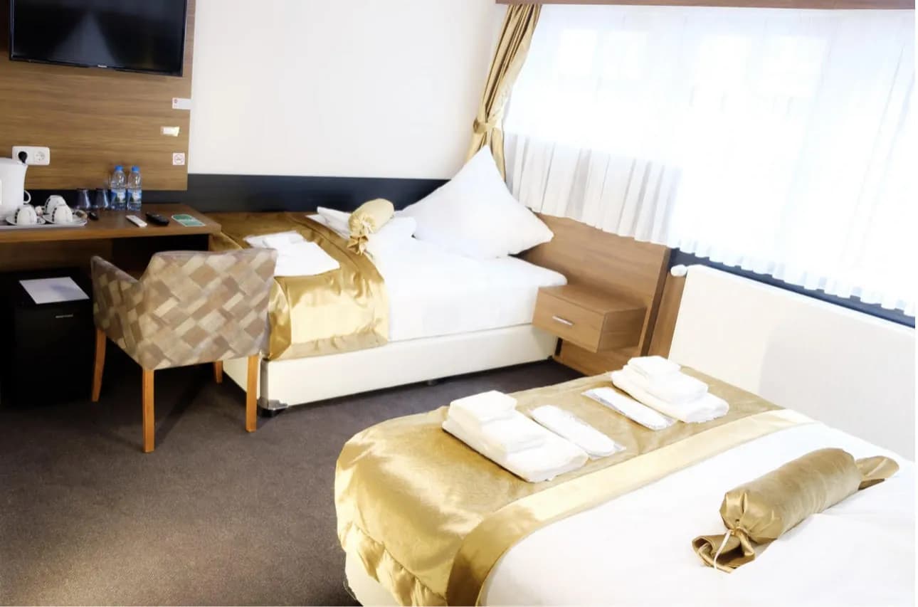 Zweibettzimmer mit zwei getrennten Betten, Schreibtisch, Sessel und Fernseher